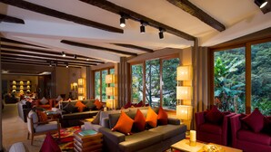 A spacious living area with a large sofa, multiple chairs, and a coffee table. There are large windows providing a view of the outdoors. - Sumaq Machu Picchu Hotel (Machu Picchu)