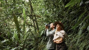 A couple in a forested area, one holding a camera.