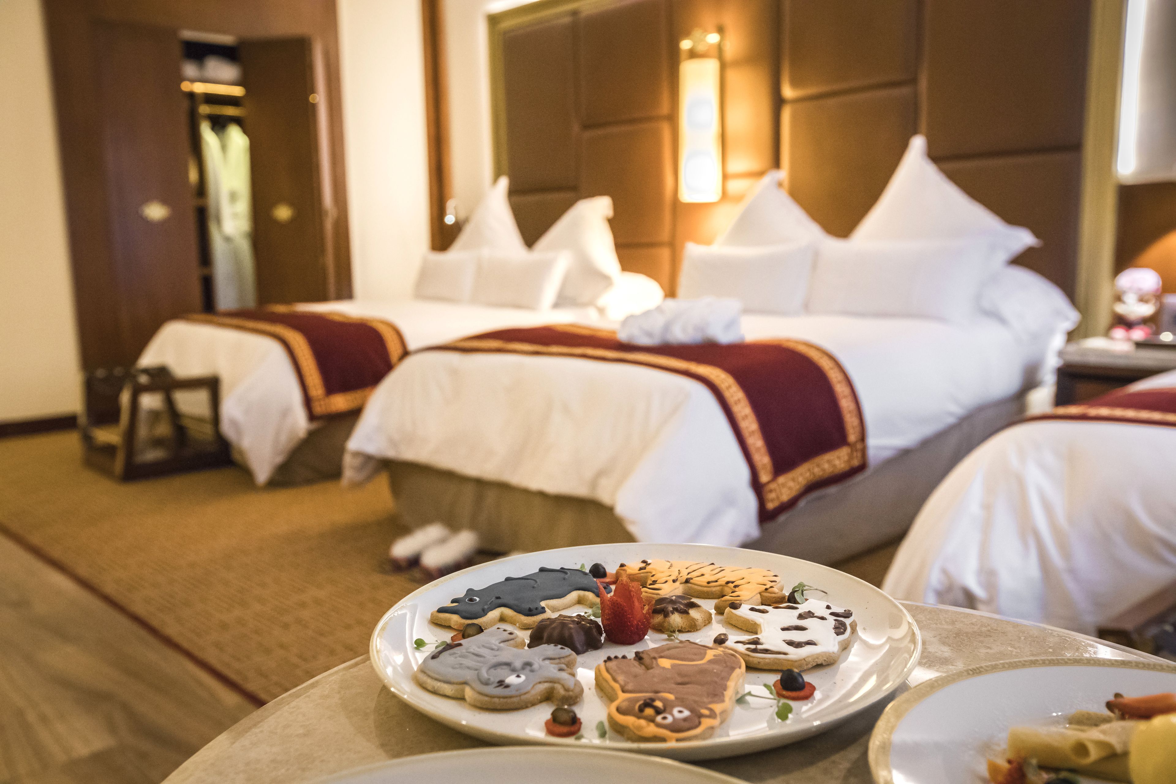 Une chambre d’hôtel avec deux lits, une table à manger avec des biscuits et un miroir au mur.