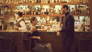 A bar area with a bartender and a customer. The bar has shelves with various bottles and glasses. - Sumaq Machu Picchu Hotel (Machu Picchu)
