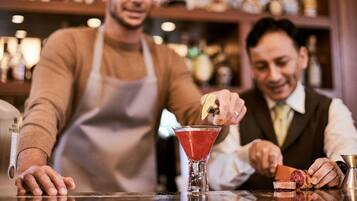 A bar setting with a bartender preparing a drink and a customer holding a slice of meat.