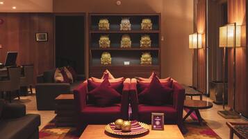 A modern living room with a red sofa, a coffee table, and a bookshelf with decorative items.