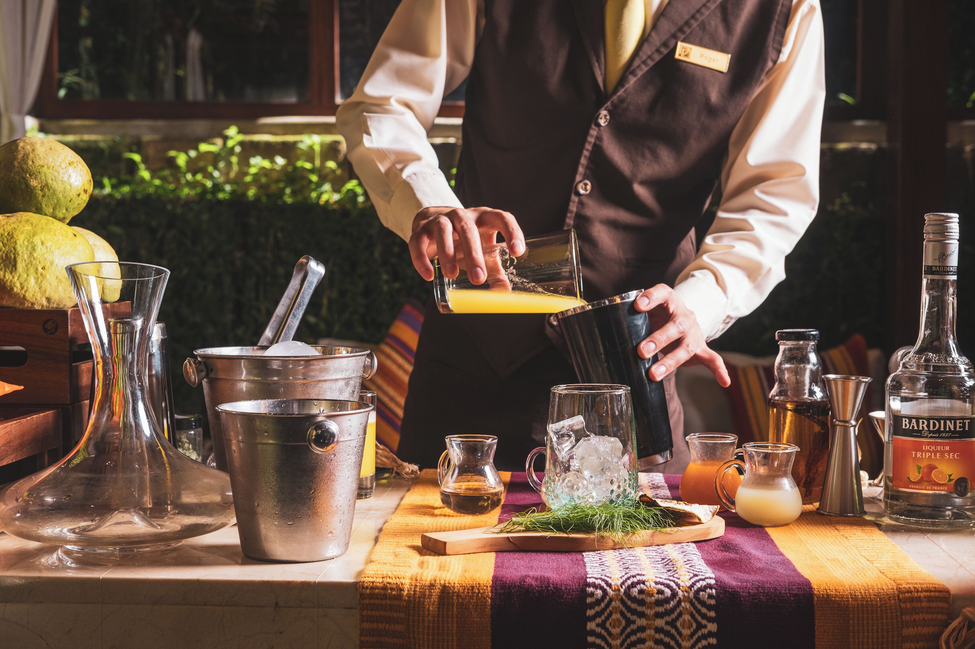 Ein Barkeeper bereitet einen Cocktail mit verschiedenen Barwerkzeugen und Flaschen auf einer Theke zu.