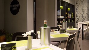Un salón de desayunos con mesas dispuestas para comer, un cartel que indica el espacio y una botella decorativa sobre la mesa.