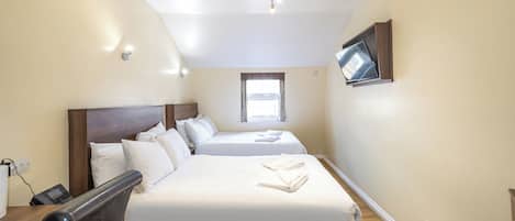 Habitación de hotel con dos camas, un televisor montado en la pared, una ventana y una lámpara en el techo.