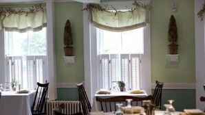 A dining area with two tables, chairs, and a radiator. - Monadnock Inn (Jaffrey)