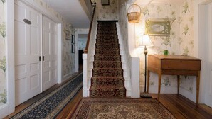 A staircase with a patterned carpet, a wooden table with a lamp, and a wall with floral wallpaper. - Monadnock Inn (Jaffrey)