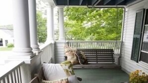 A porch with a wooden bench and a bench with cushions. - Monadnock Inn (Jaffrey)