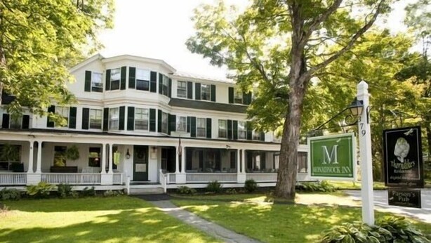 A two-story building with a white facade and green shutters, a covered front porch, and a sign for the "M" Inn. - Monadnock Inn (Jaffrey)
