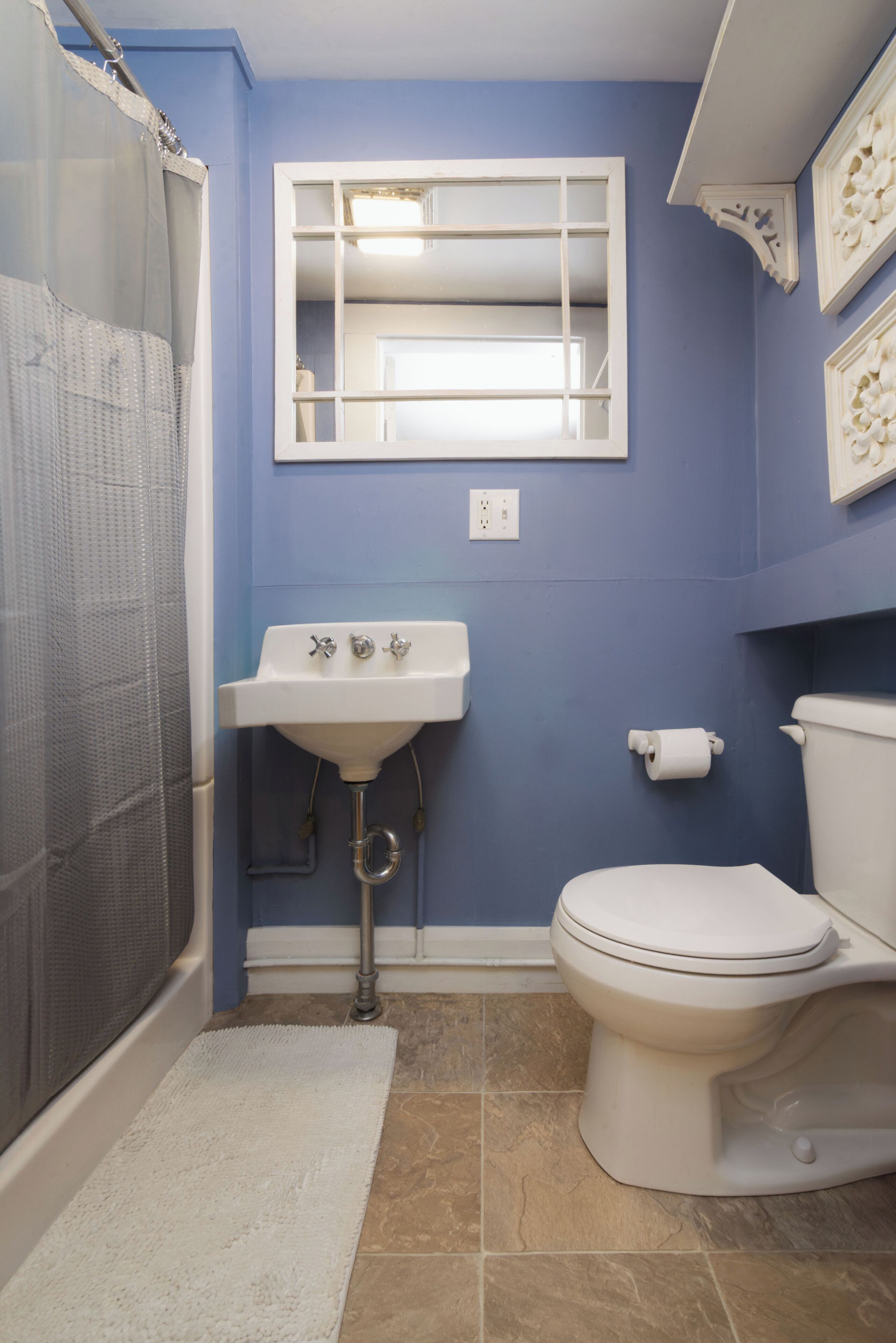 Une salle de bain avec un lavabo, des toilettes et une douche, le tout de couleur blanche.
