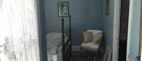 A bedroom with a bed, a chair, a radiator, and a picture on the wall.
