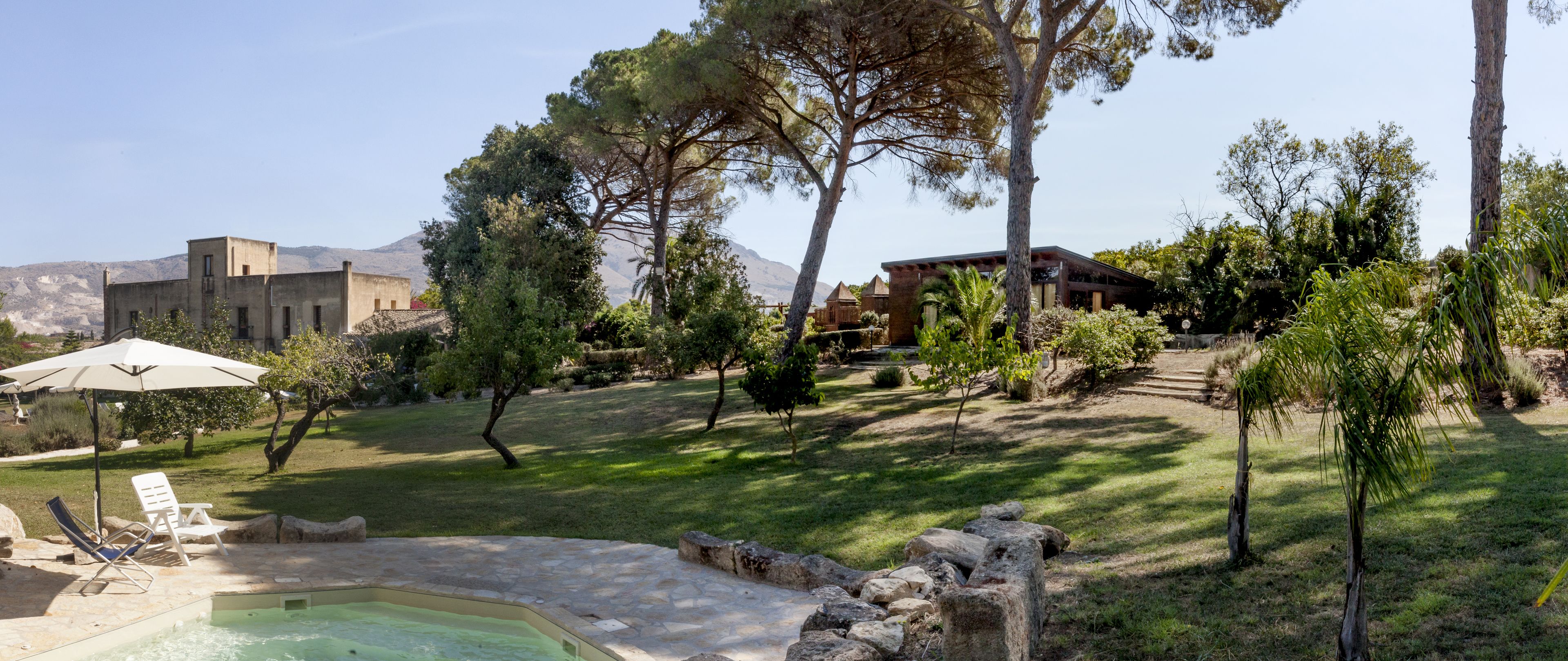 Un área de piscina con sillones de descanso, un sendero de piedra y una terraza de madera.