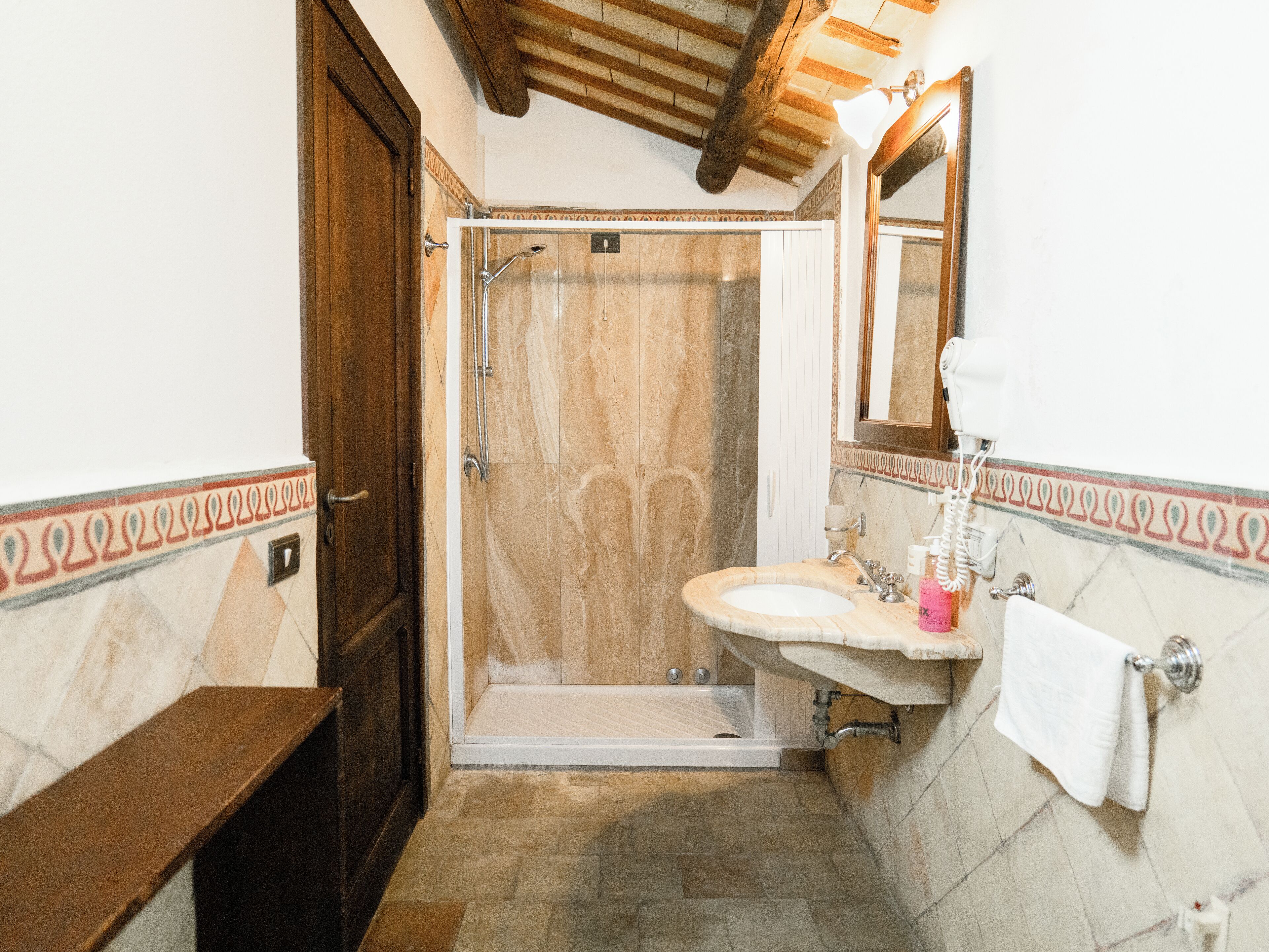 Un baño con ducha, lavamanos y espejo.