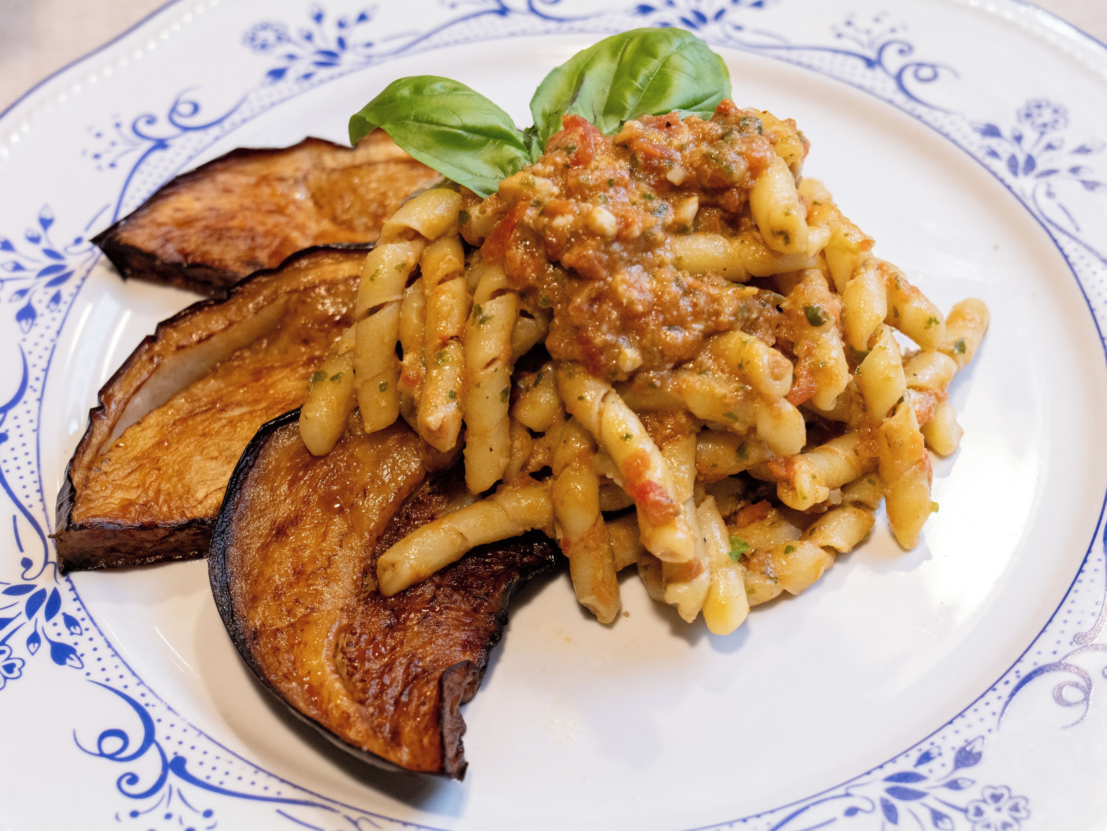 Eine Pasta-Zahl mit Tomatensauce, dazu gegrillte Auberginenscheiben und ein Basilikumblatt.