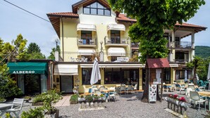 Een gebouw met twee verdiepingen, terras en een restaurant genaamd 'Albergo'.