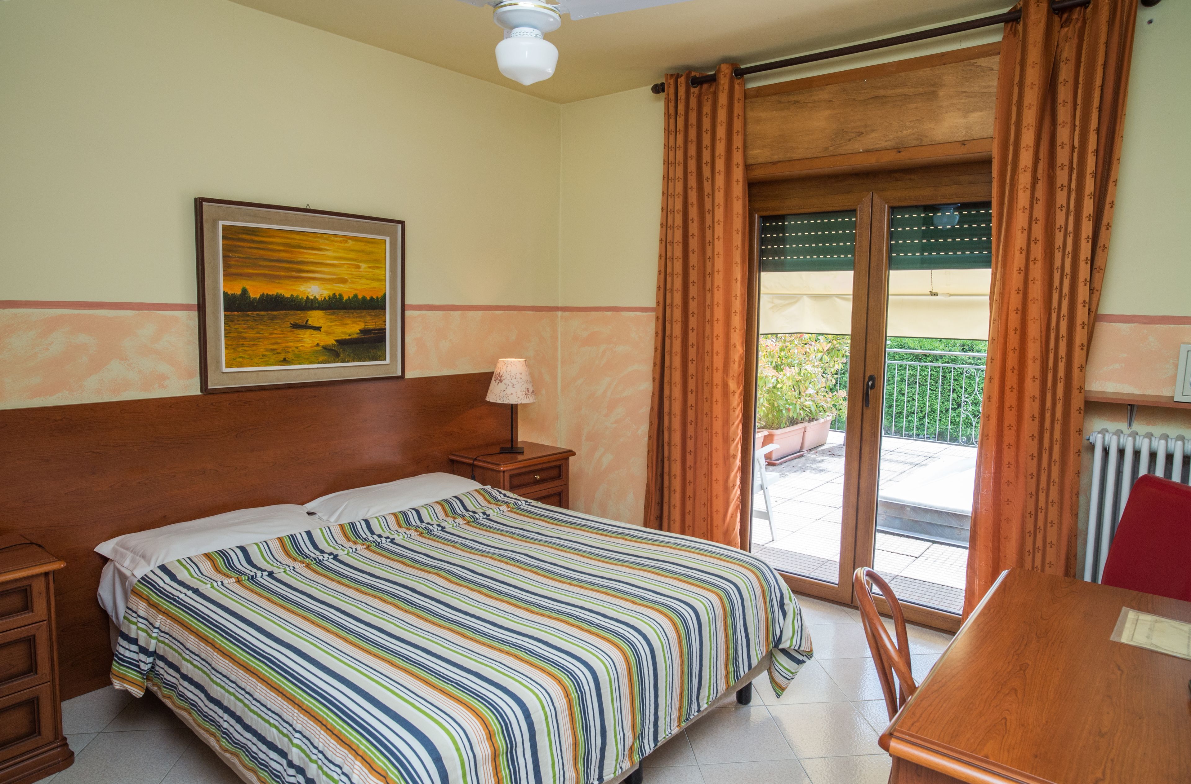 Een hotelkamer met een bed, nachtkastje, tafel en uitzicht.