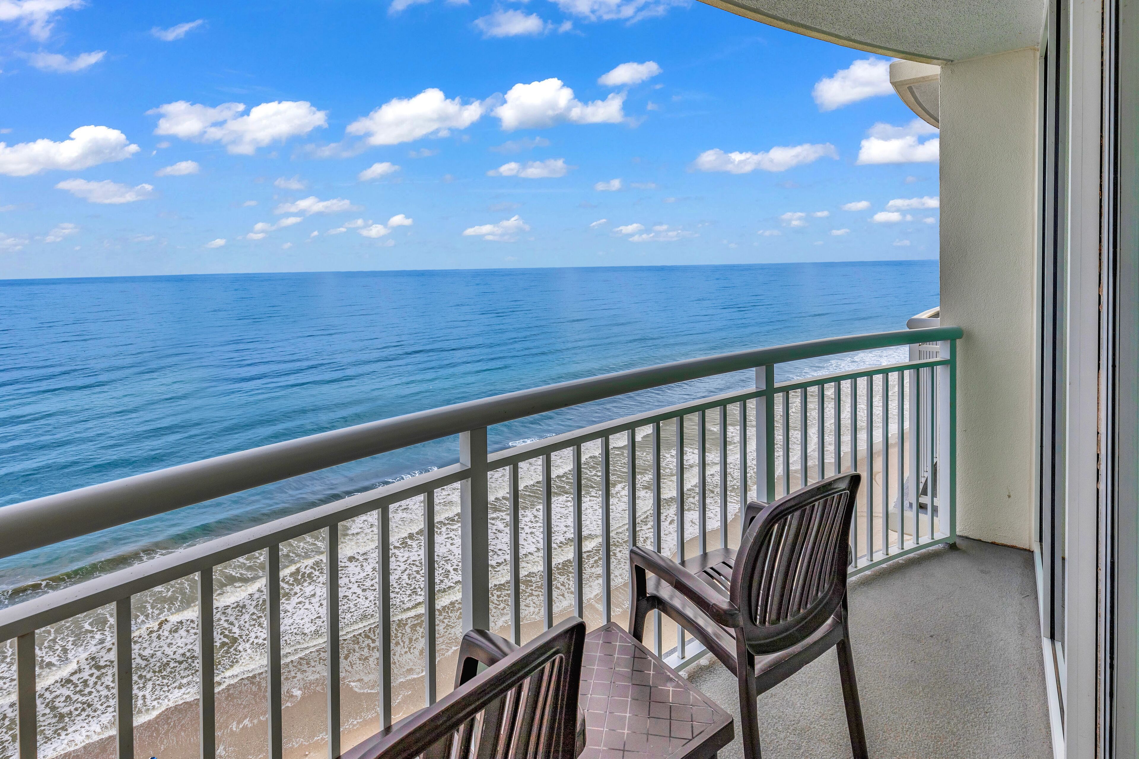 A balcony with a view of the ocean and beach.