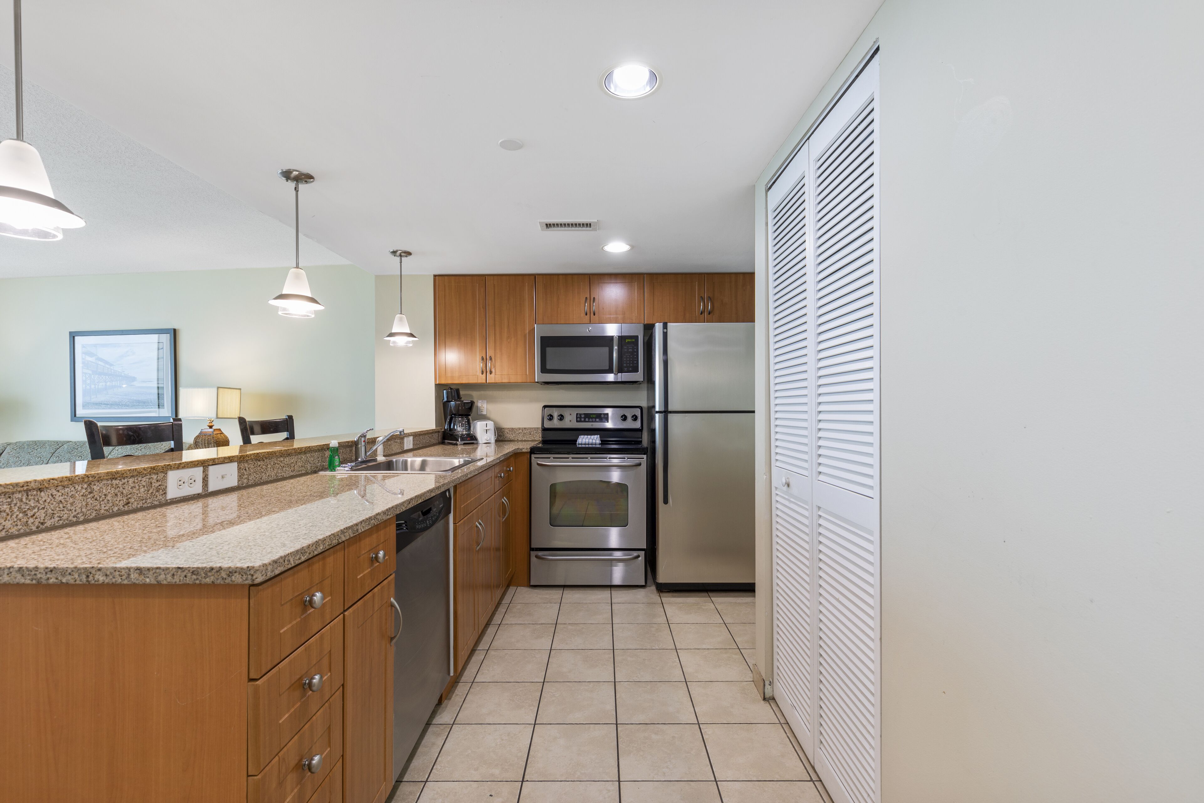 A modern kitchen with wooden cabinets, stainless steel appliances, and a tiled floor.