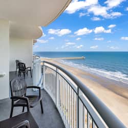 Enjoy ocean views from this balcony with a pier in the distance, perfect for relaxation.