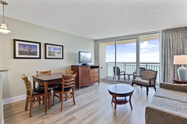 A spacious living area with a dining table, chairs, a sofa, and a TV.