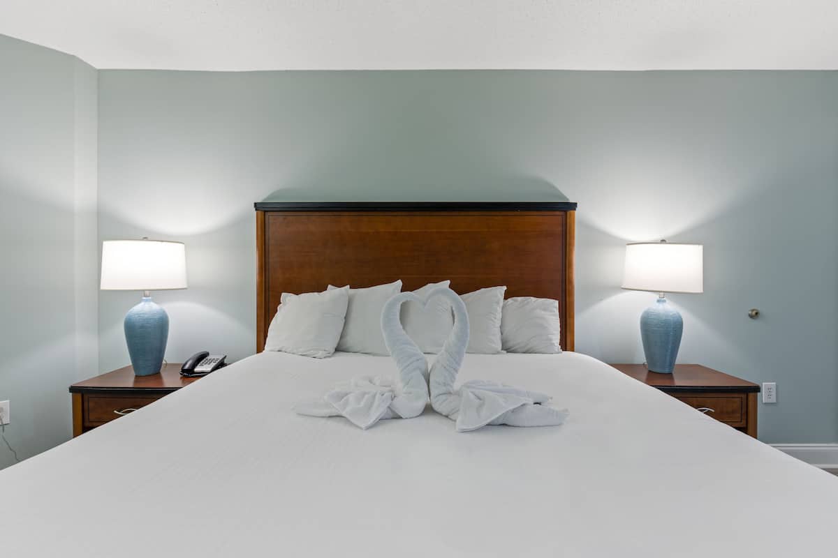 Una habitación de hotel con una cama grande, dos lámparas de noche y un cabecero de madera.