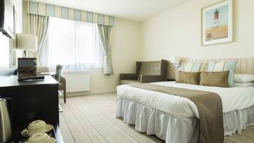 Ein Hotelzimmer mit einem Bett, einem Schreibtisch mit einem Laptop, einem Sessel und einem Esstisch.