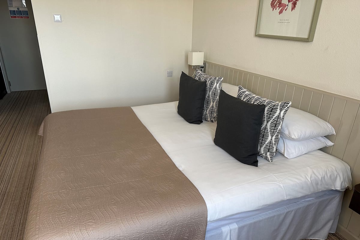 Habitación de hotel con una cama grande, una mesita de noche, una lámpara y un cuadro en la pared.