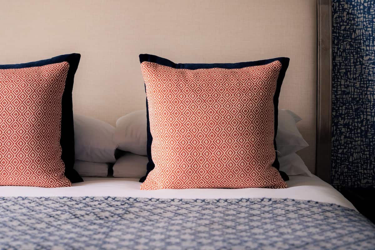 Una cama con dos almohadas, un edredón estampado y una pared azul con textura.