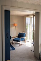 Una habitación con una silla azul, una lámpara de pie y vistas al exterior.
