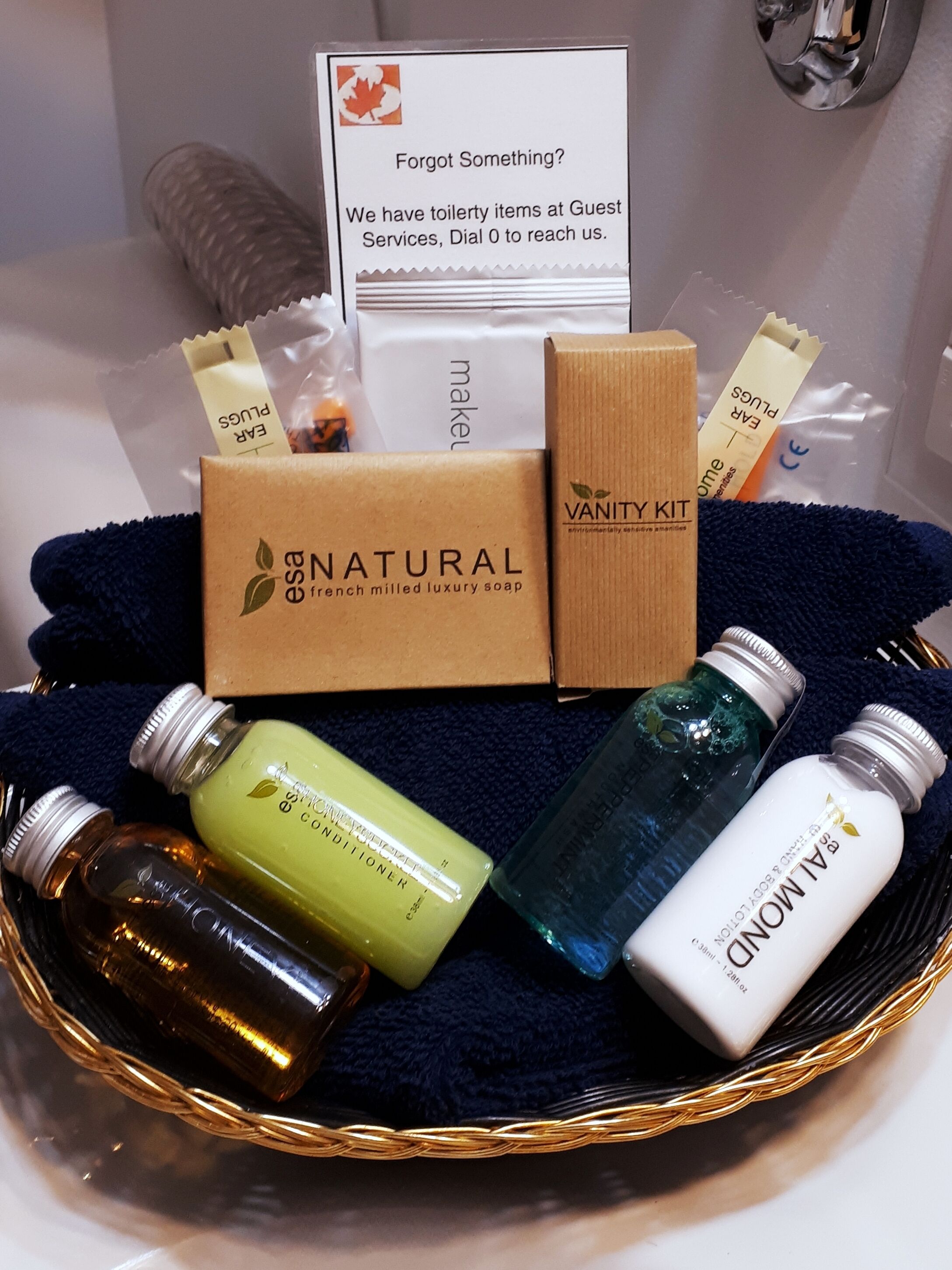 Un cesto con articoli da toilette, tra cui una saponetta naturale, un kit da toeletta e diverse bottiglie di balsamo e lozione.