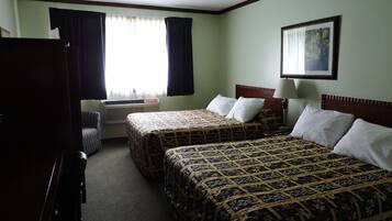 A hotel room with two beds, a desk, a chair, a TV, and a window with curtains.