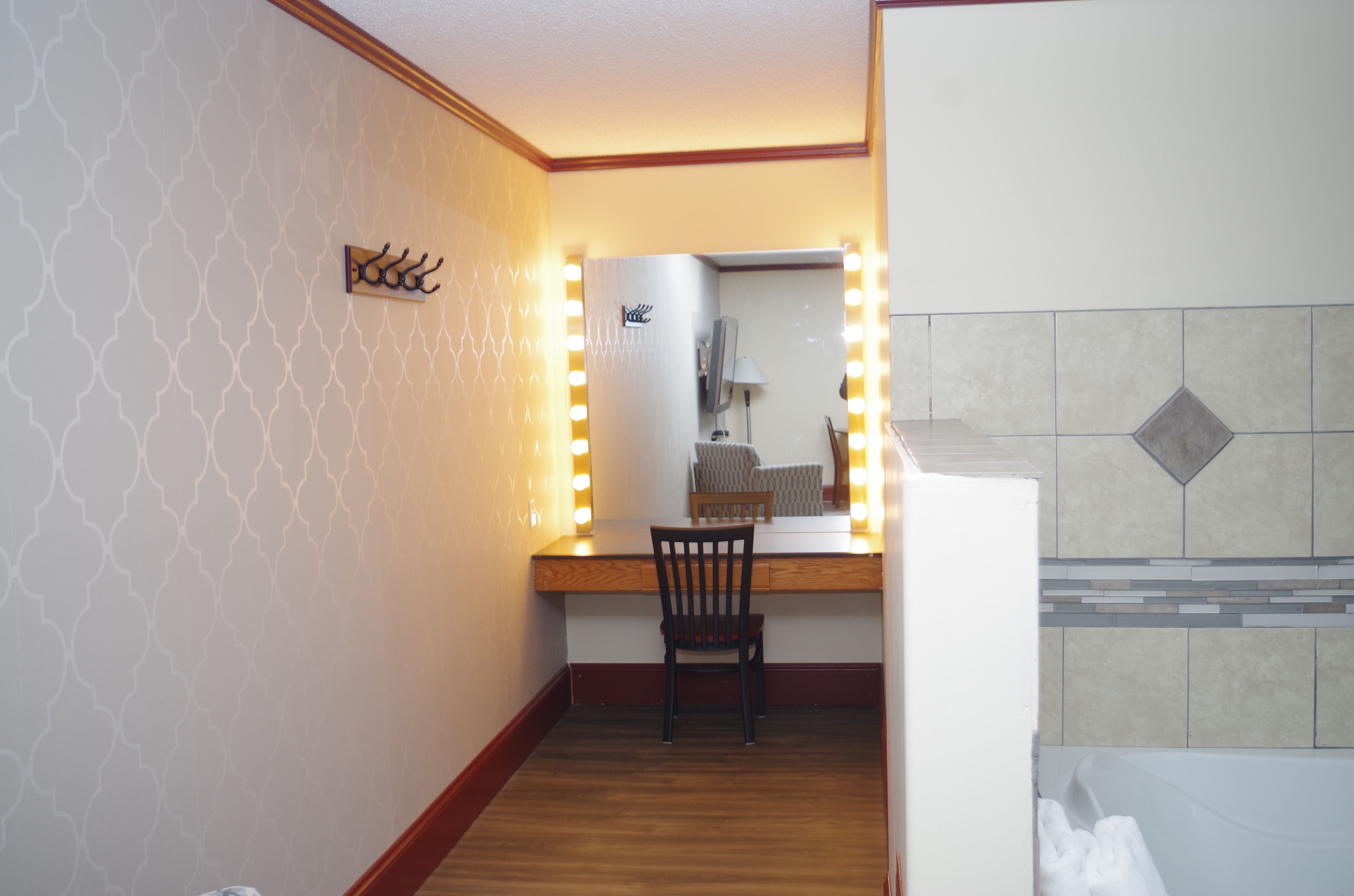 A room with a vanity mirror, chair, and a wall-mounted light fixture.