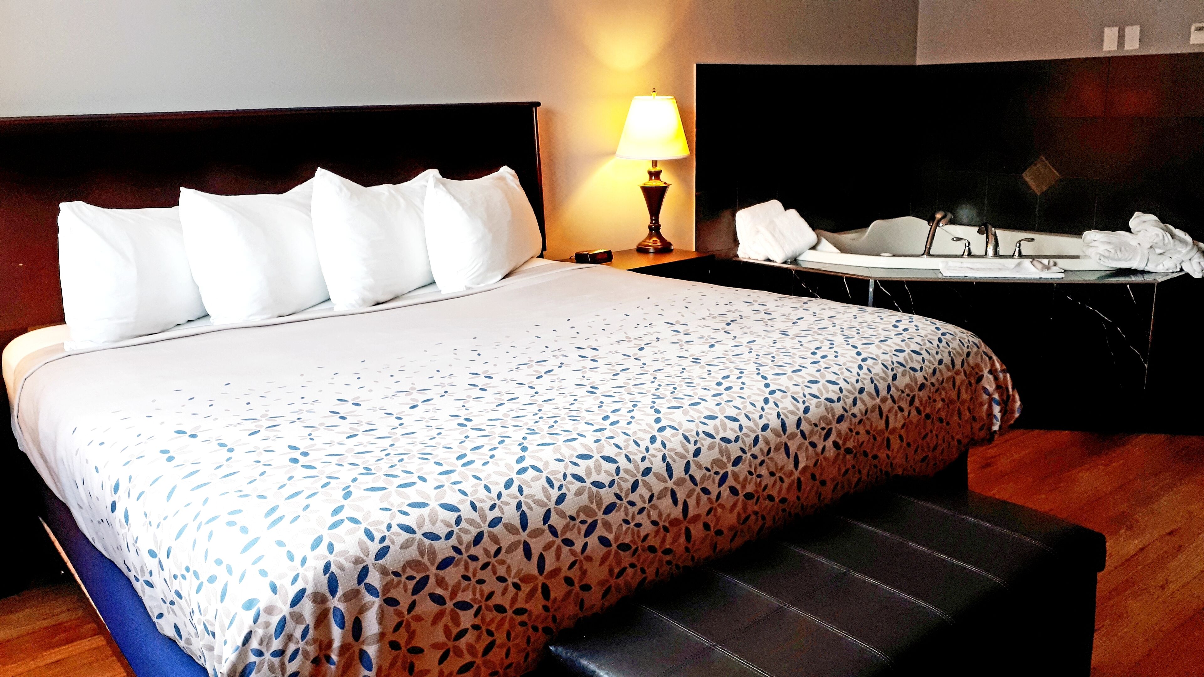 Una habitación de hotel con una cama bien hecha, una mesita de noche con lámpara y una pequeña mesa con toallas.