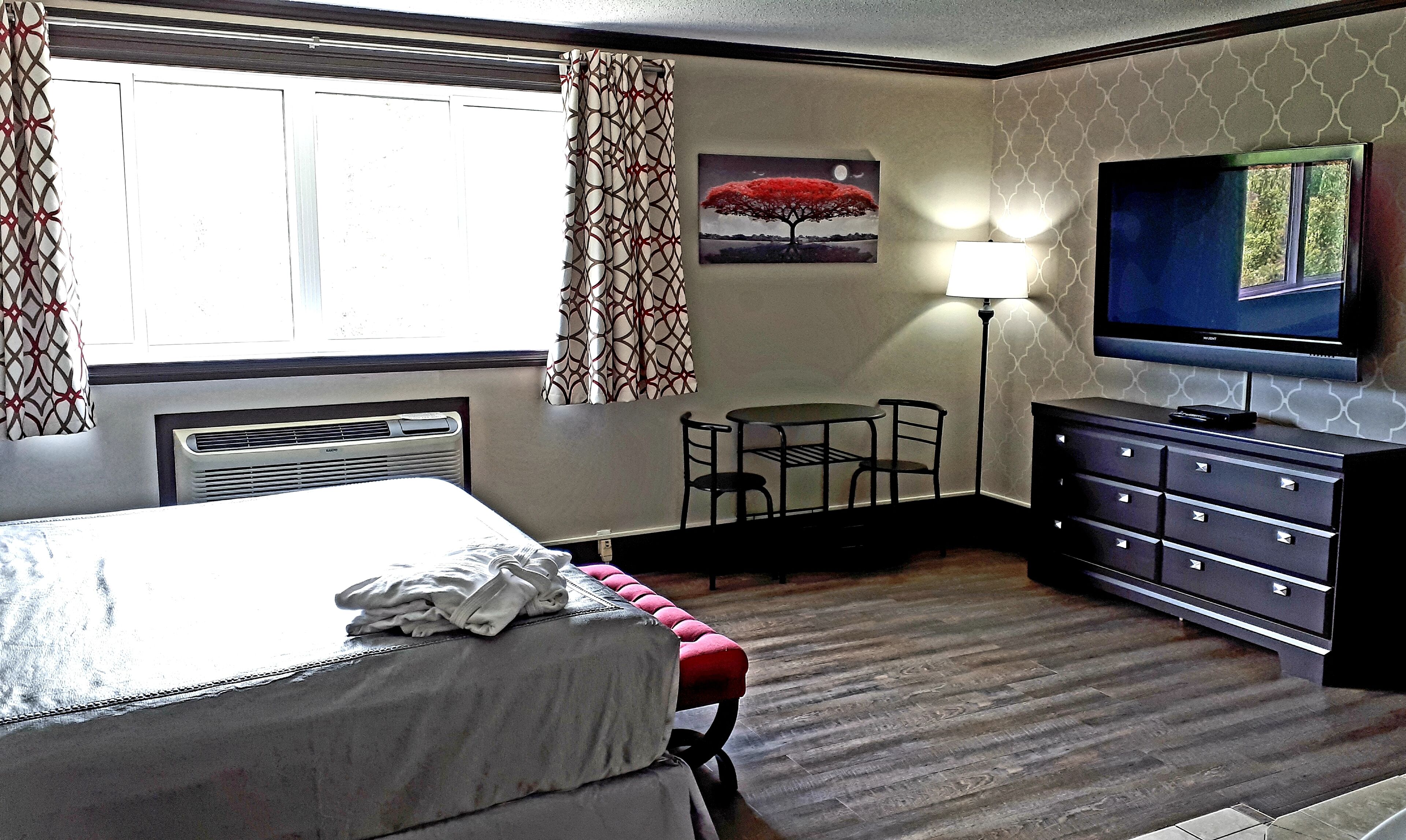 Une chambre d’hôtel comprenant un lit, un bureau avec une chaise, une télévision et une lampe.