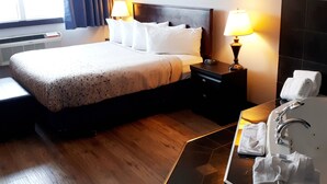 Habitación de hotel con cama, lámparas de noche, mesita de noche, baño con lavamanos y espejo, y ventana con cortinas.