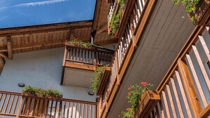 A multi-story building with wooden balconies, each with a railing and potted plants. - Hotel Alle Piramidi (Segonzano)
