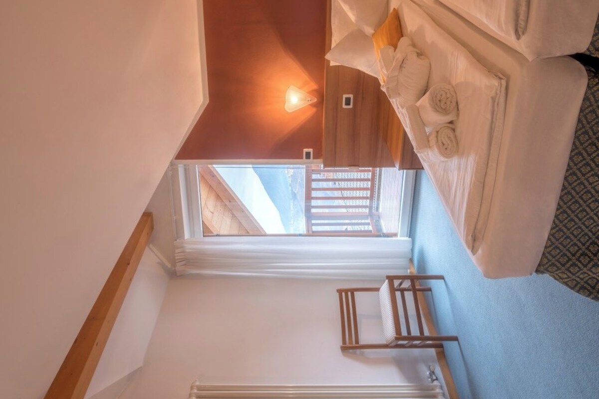 A compact room with a bed, a small table, and a window.