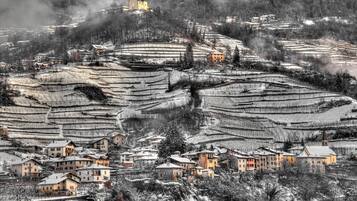 Un villaggio innevato con campi a terrazze e una chiesa su una collina.