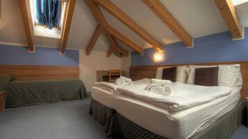 Un dormitorio con una cama grande, una cama más pequeña, una mesita de noche, un aparador y una ventana con cortinas.