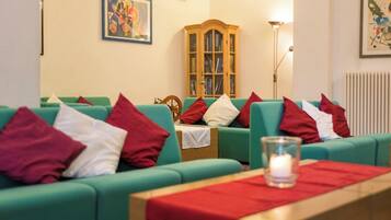 A room with green sofas, red and white cushions, a wooden cabinet, and a framed picture on the wall.