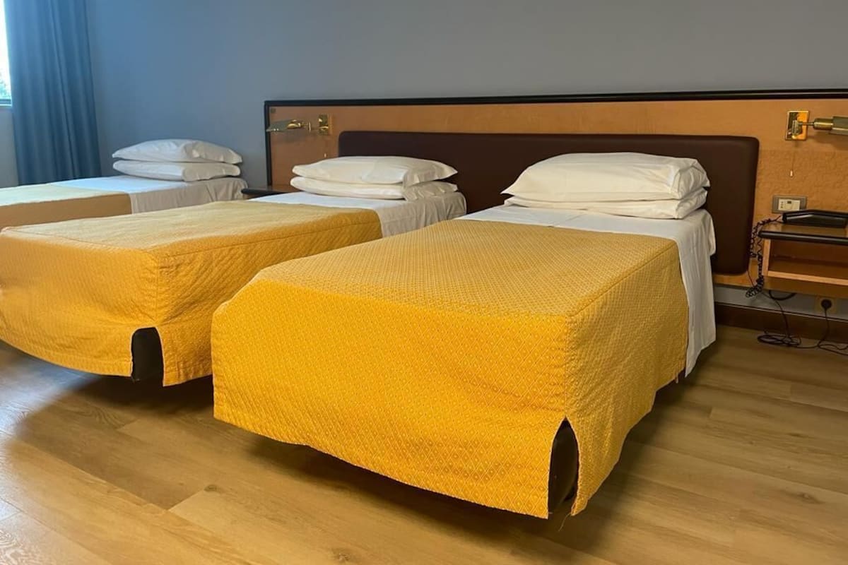 Ein Hotelzimmer mit zwei Einzelbetten, jeweils mit gelber Bettdecke und weißen Kissen.