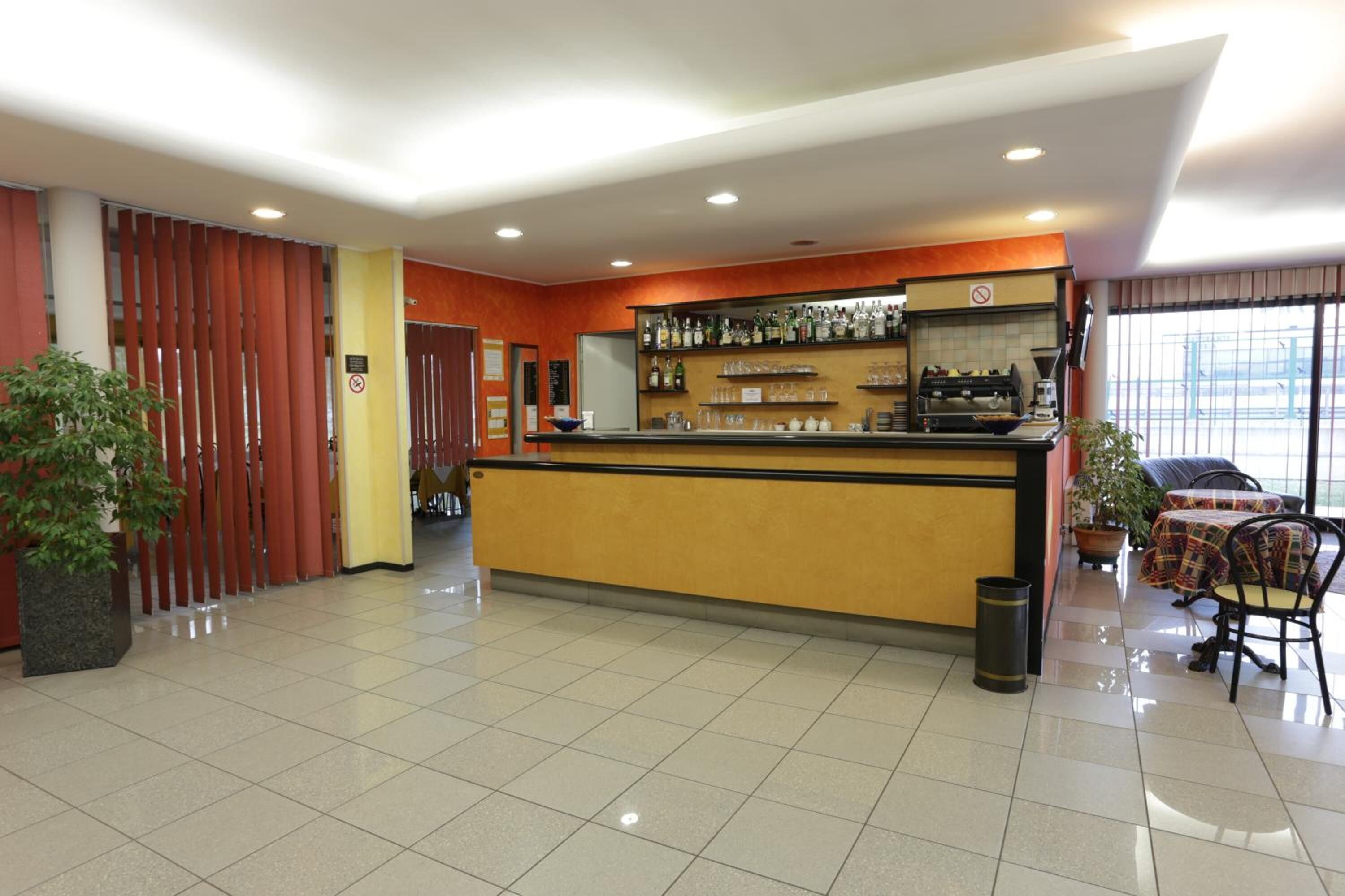 Eine Hotelhalle mit einer Rezeption, einer Kaffeemaschine und einer Sitzecke mit Tisch und Stühlen.