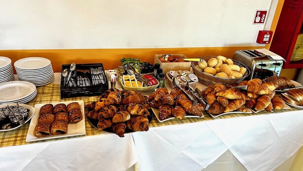 A buffet table with various food items including pastries, bread, and condiments. - Art & Hotel Treviolo (Treviolo)