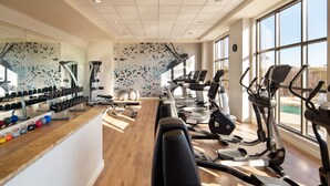 Ein Fitnessstudio mit Laufbändern, Crosstrainern und Kurzhanteln.