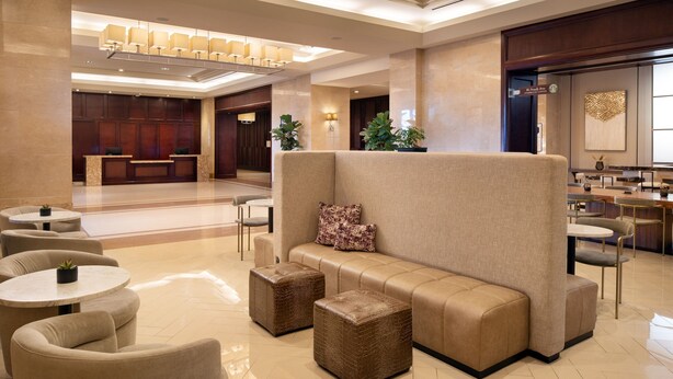 Eine moderne Lobby mit Sitzgelegenheiten, einer Rezeption und einem Essbereich.