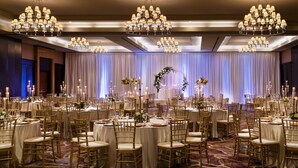 A banquet hall with round tables, gold chairs, chandeliers, and draped curtains. - Sheraton Garden Grove-Anaheim South Hotel (Garden Grove)