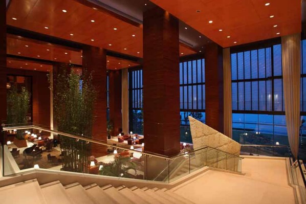 Un hall espacioso con una escalera, ventanas amplias y plantas de interior.