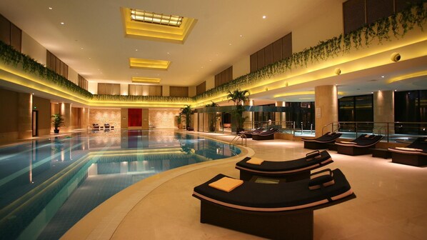 A large indoor swimming pool with sun loungers and a red door in the background. - Kempinski Hotel Suzhou (Suzhou)