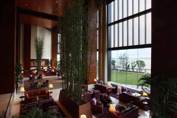 A spacious lobby with a high ceiling, large windows offering a view of the outdoors, and a variety of seating arrangements. - Kempinski Hotel Suzhou (Suzhou)