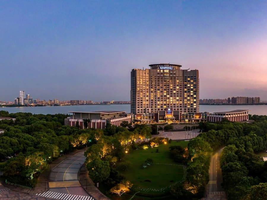A high-rise hotel with a view of a river and city skyline at dusk.